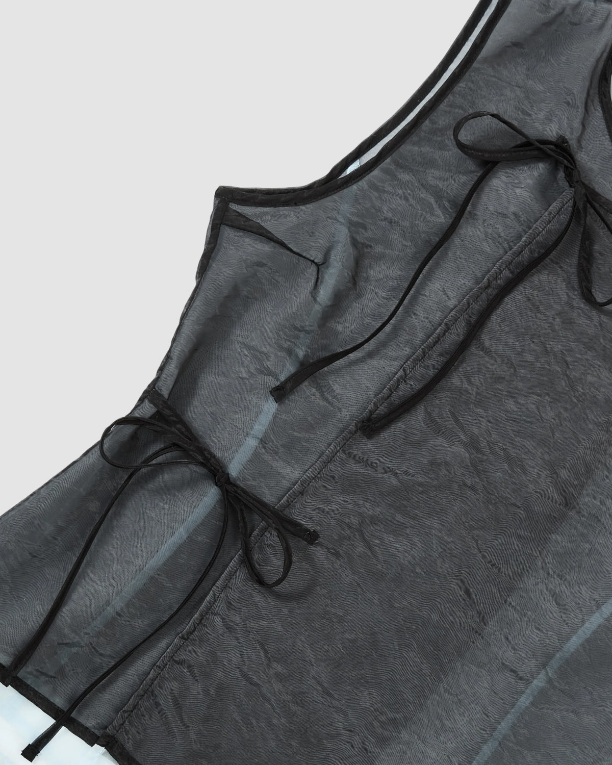 Close-up of Sundae School’s BLACK VITA ORGANZA VEST—sleeveless and double-layered with sheer black mesh over sky blue, two thin Korean goreum ties at the side, a slightly crinkled texture, and black trim along the edges.