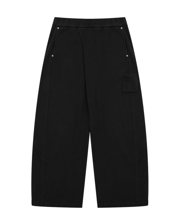 BLACK WASH WRAP SWEAT BAJI by Sundae School, featuring a wide-leg silhouette in black cotton with front pockets and a small square patch pocket on the upper left leg, displayed flat against a white background.