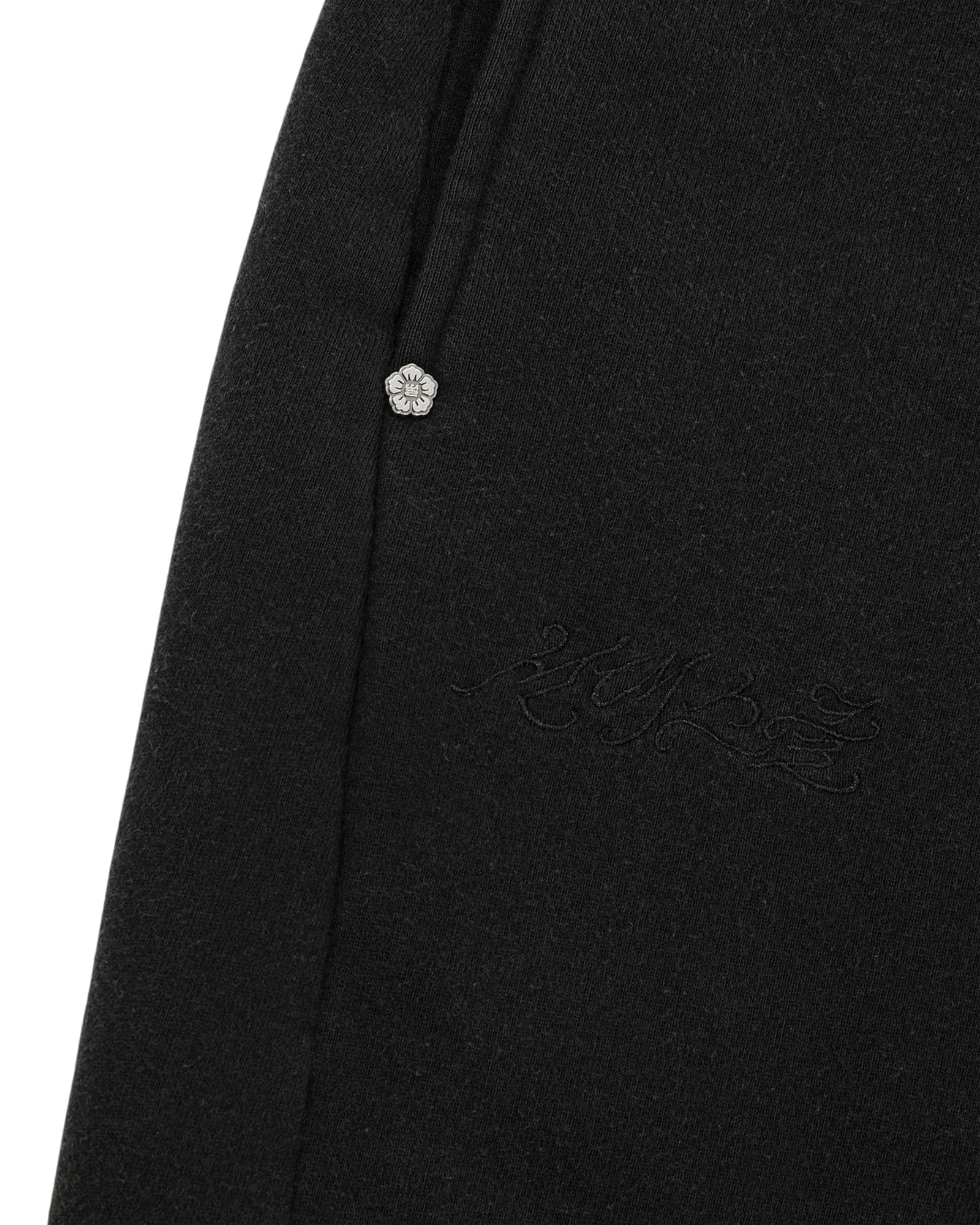 Close-up of the BLACK WASH WRAP SWEAT BAJI by Sundae School, featuring a black fabric with a pocket seam, a drawstring with a silver tip, and subtle embroidered script near the pocket.