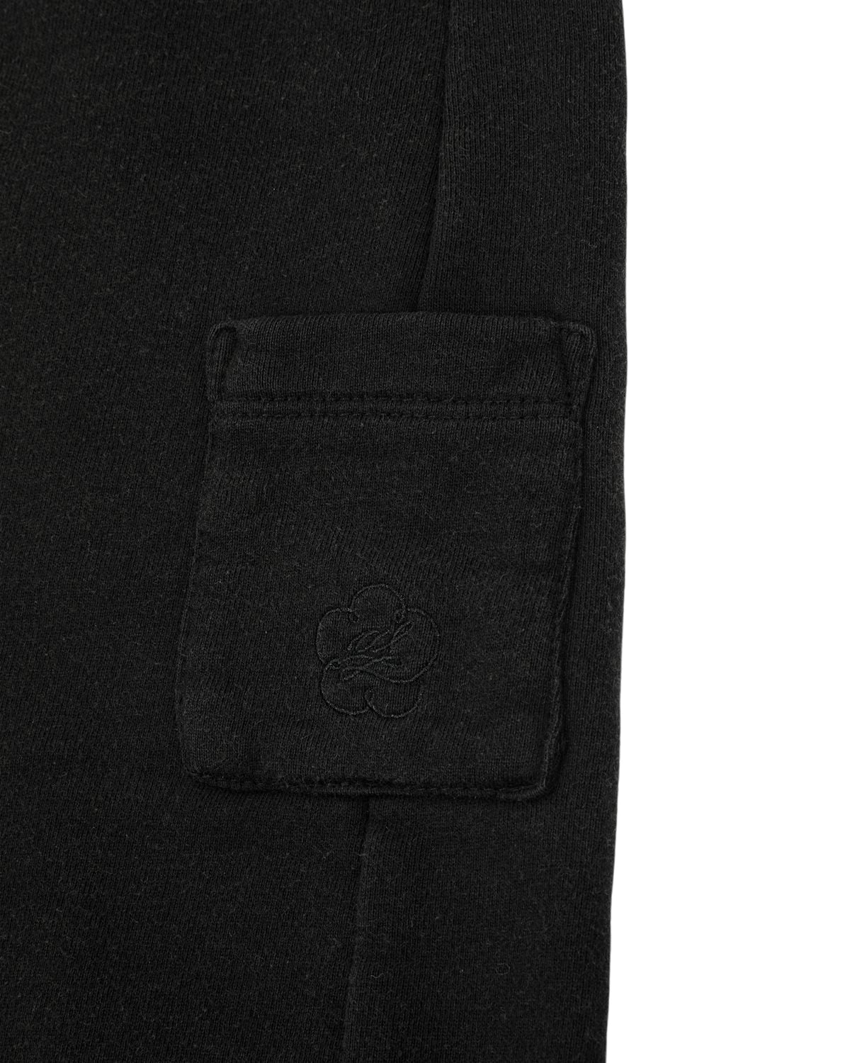 BLACK WASH WRAP SWEAT BAJI by Sundae School: Black cotton sweatpants featuring a small side rectangular pocket adorned with a subtle embroidered flower motif and secured with a snap button closure.