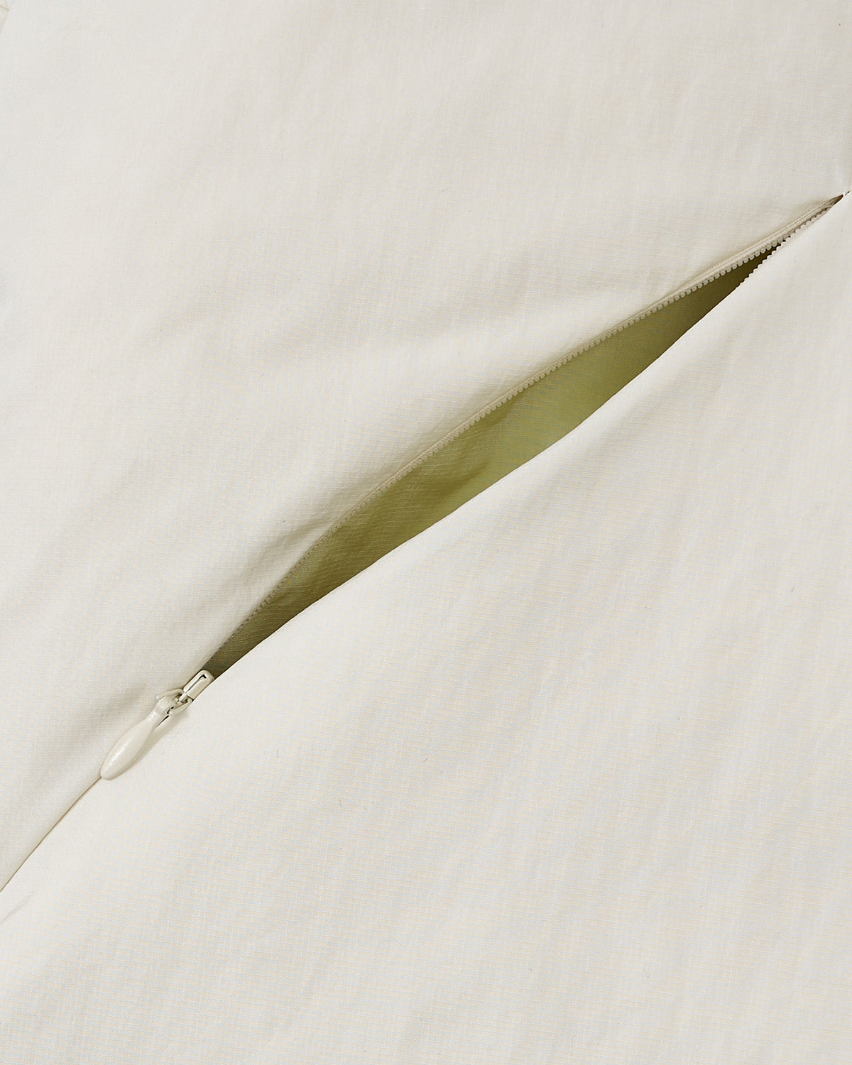 A close-up of the Sundae School IVORY LIME ORIGAMI PUFFER shows a partially opened zipper on the left, revealing the inside of the pillow.