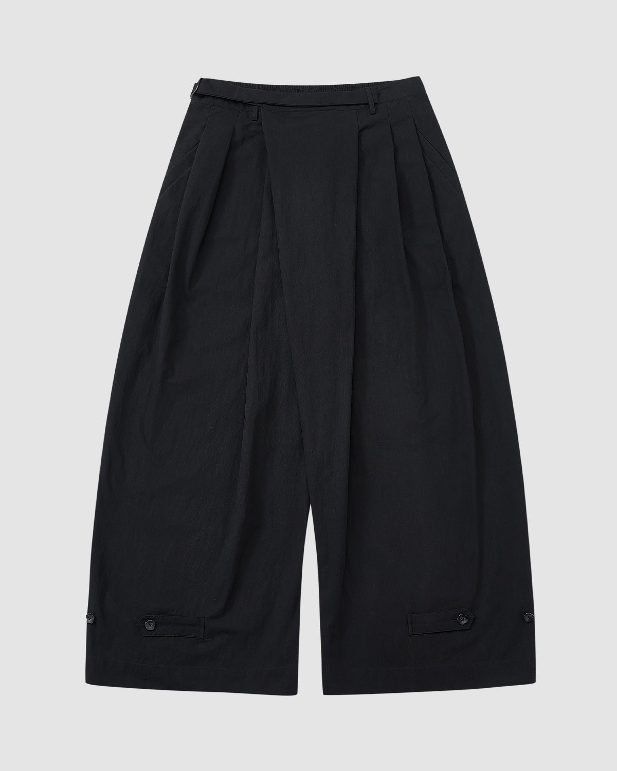 Sundae School’s BLACK PLEATED PALAZZO PANTS feature wide legs, pleats at the waist, a high waistband, mochi button details near the hem, and a mid-calf length. Shown on a light gray background.