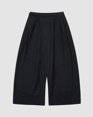 Sundae School’s BLACK PLEATED PALAZZO PANTS feature wide legs, pleats at the waist, a high waistband, mochi button details near the hem, and a mid-calf length. Shown on a light gray background.