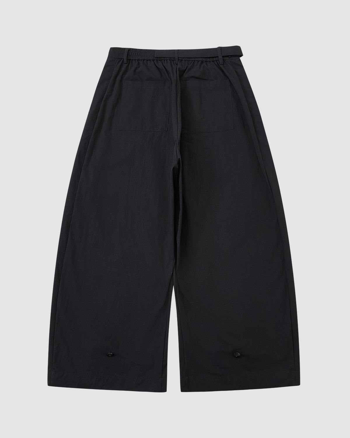 The BLACK PLEATED PALAZZO PANTS from Sundae School are shown laid flat on a light gray background, featuring an elastic waistband, belt loops, two large back pockets, and mochi button details near each pant leg's hem.