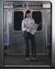 A person stands on a subway train wearing Sundae School FLARE SKIRT PANTS, paired with a light blue shirt and black heels. Subway doors and a metal railing are visible in the background.