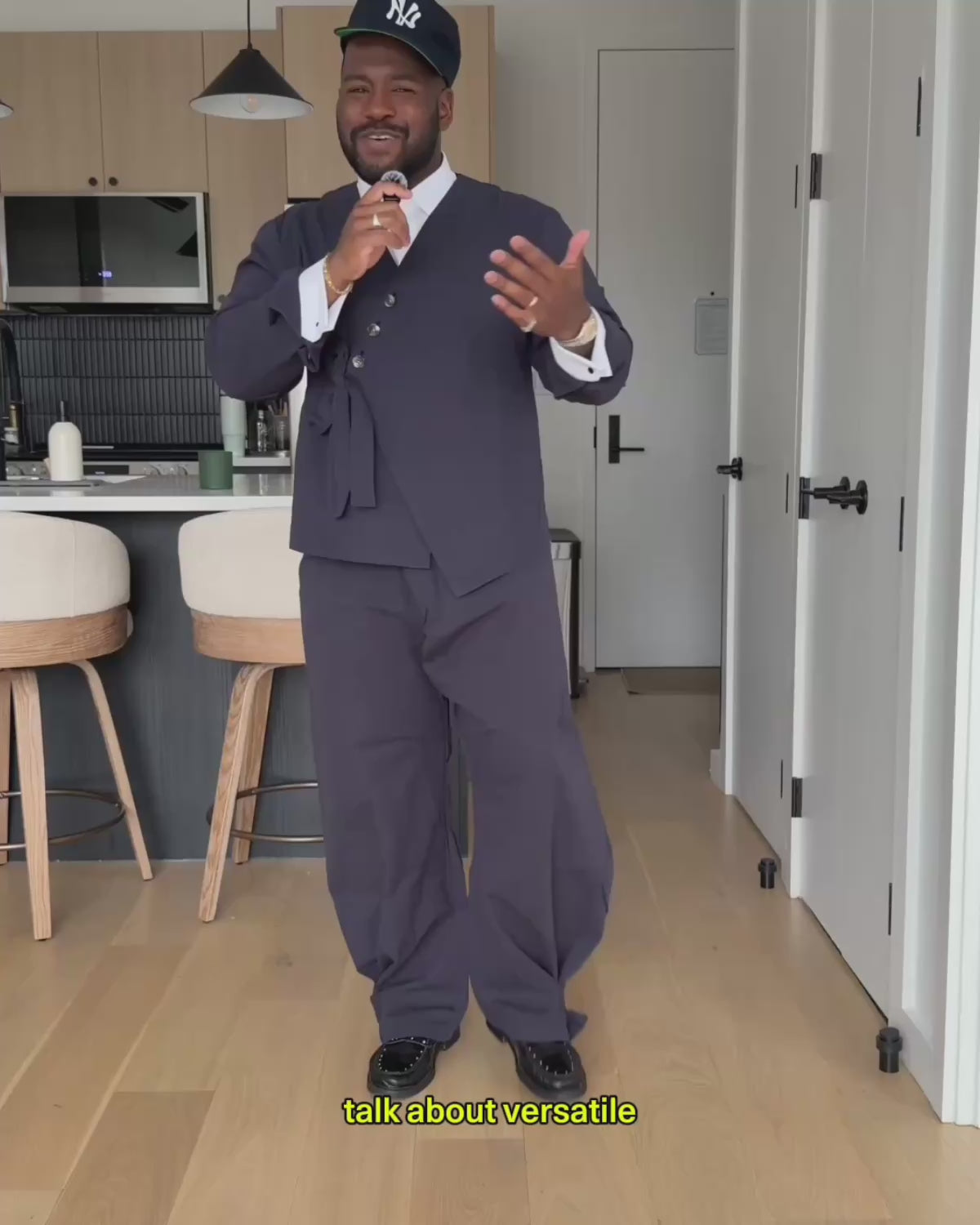 A video review and try-on of Sundae School's Navy Hanbok Tie Blazer and Balloon Pants set. The creator unboxes the package and demonstrates how to style the versatile dark navy suit both casually with a t-shirt and cap or dressed up with the jacket tied at the waist, highlighting details like the sleeve stash pocket and adjustable pant hem buttons.