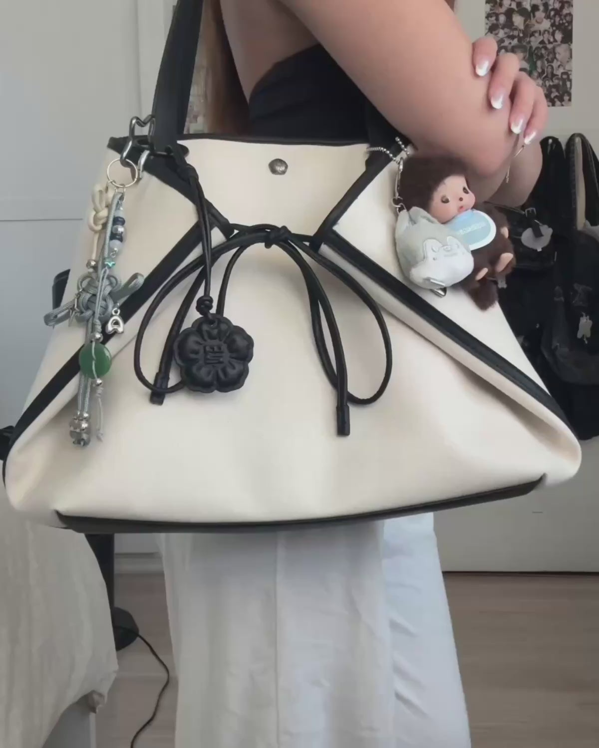 A video demonstrating how to pack and style a cream-colored Sundae School canvas tote bag trimmed in black. A person packs everyday essentials like a tablet, planner, journal, Mochi gummies, and sunglasses into the bag's organized compartments, then models different ways to wear and carry the tote.