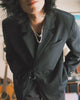 A streetwear lookbook video featuring a man styling Korean-inspired outfits from Sundae School. He demonstrates multiple versatile looks in a sunlit room, combining a black Hanbok-style tie blazer and wide-leg trousers with ribbed tank tops, plaid flannel shirts, denim button-ups, and white tees.